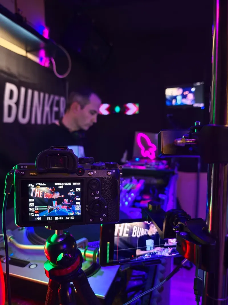 Cámara grabando a un DJ, con un móvil filmando el mismo set al lado